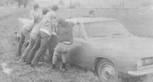 A car is pushed over by some kids (reenactment).